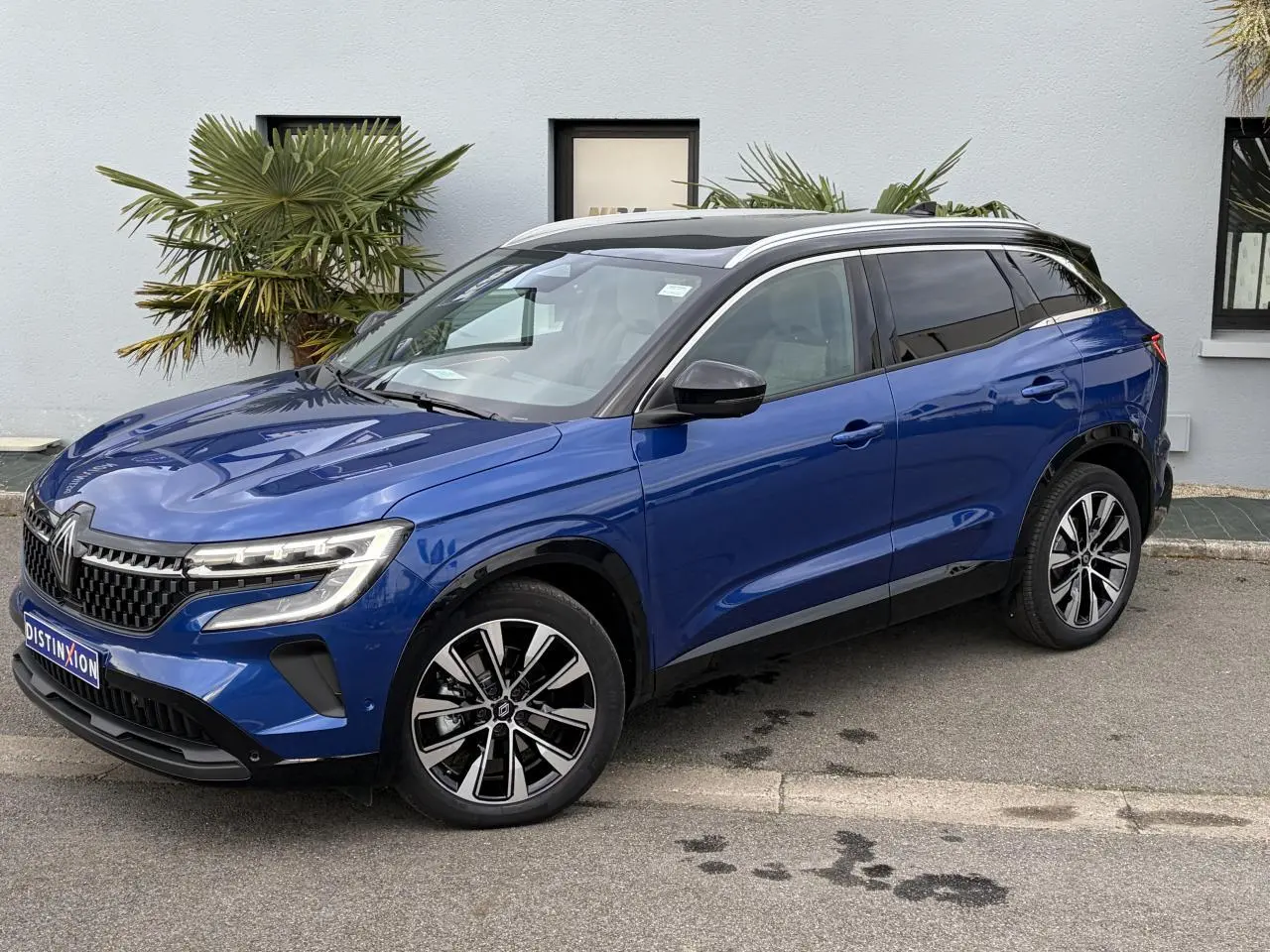 Renault Austral E-Tech hybride bleu Iron avec toit noir, vue 3/4 avant droit, jantes alliage noires diamantées.