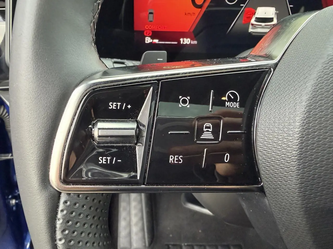 Gros plan sur les commandes au volant gauche du Renault Austral bleu, avec affichage digital rouge en arrière-plan.