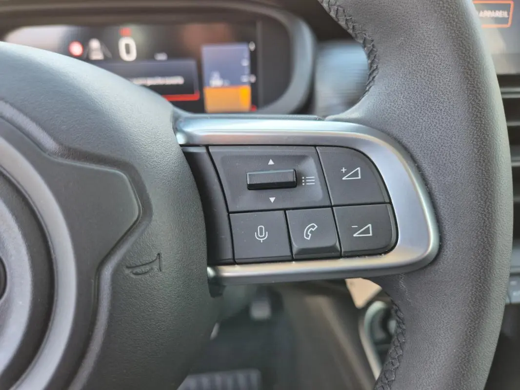 Gros plan sur les commandes au volant côté droit du Jeep Avenger noir 2024, avec boutons de volume et téléphone.