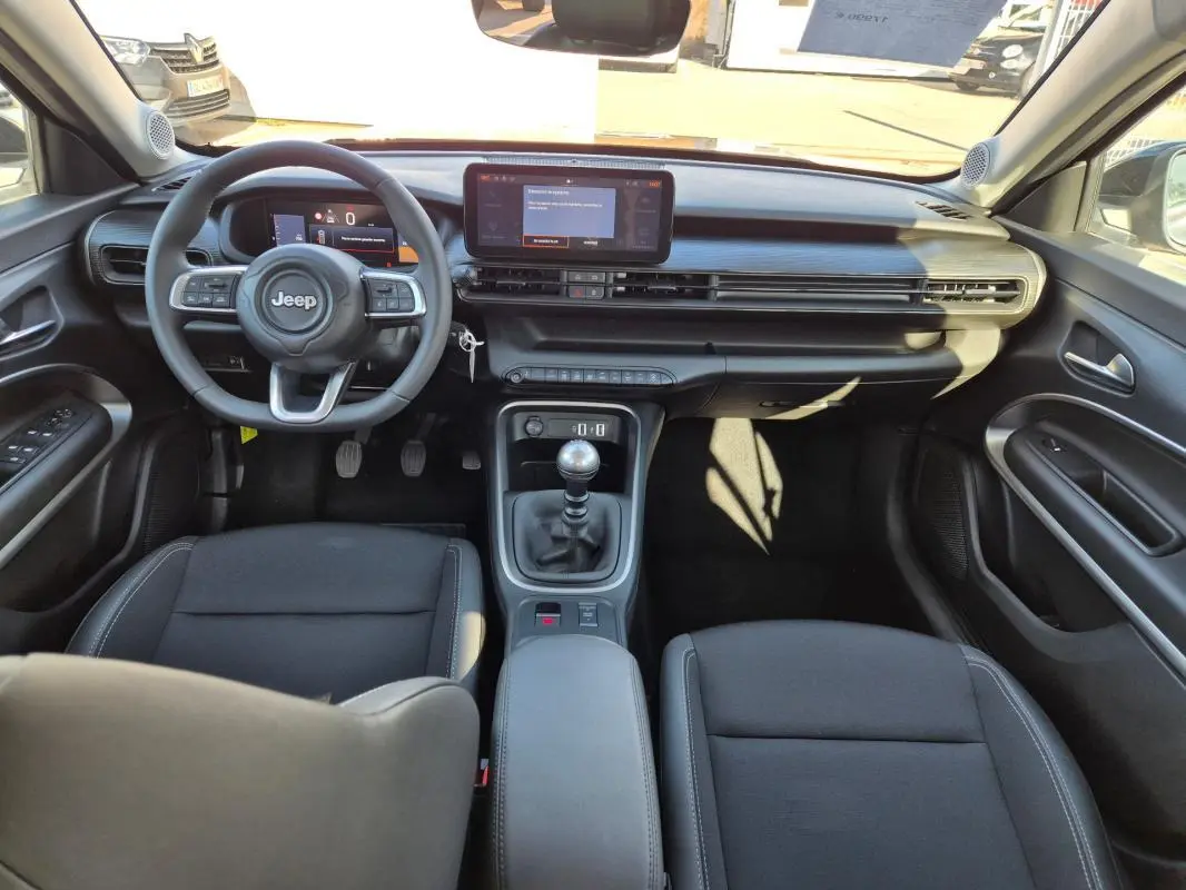 Vue intérieure avant du Jeep Avenger noir 2024, tableau de bord moderne avec écran tactile et boîte manuelle.