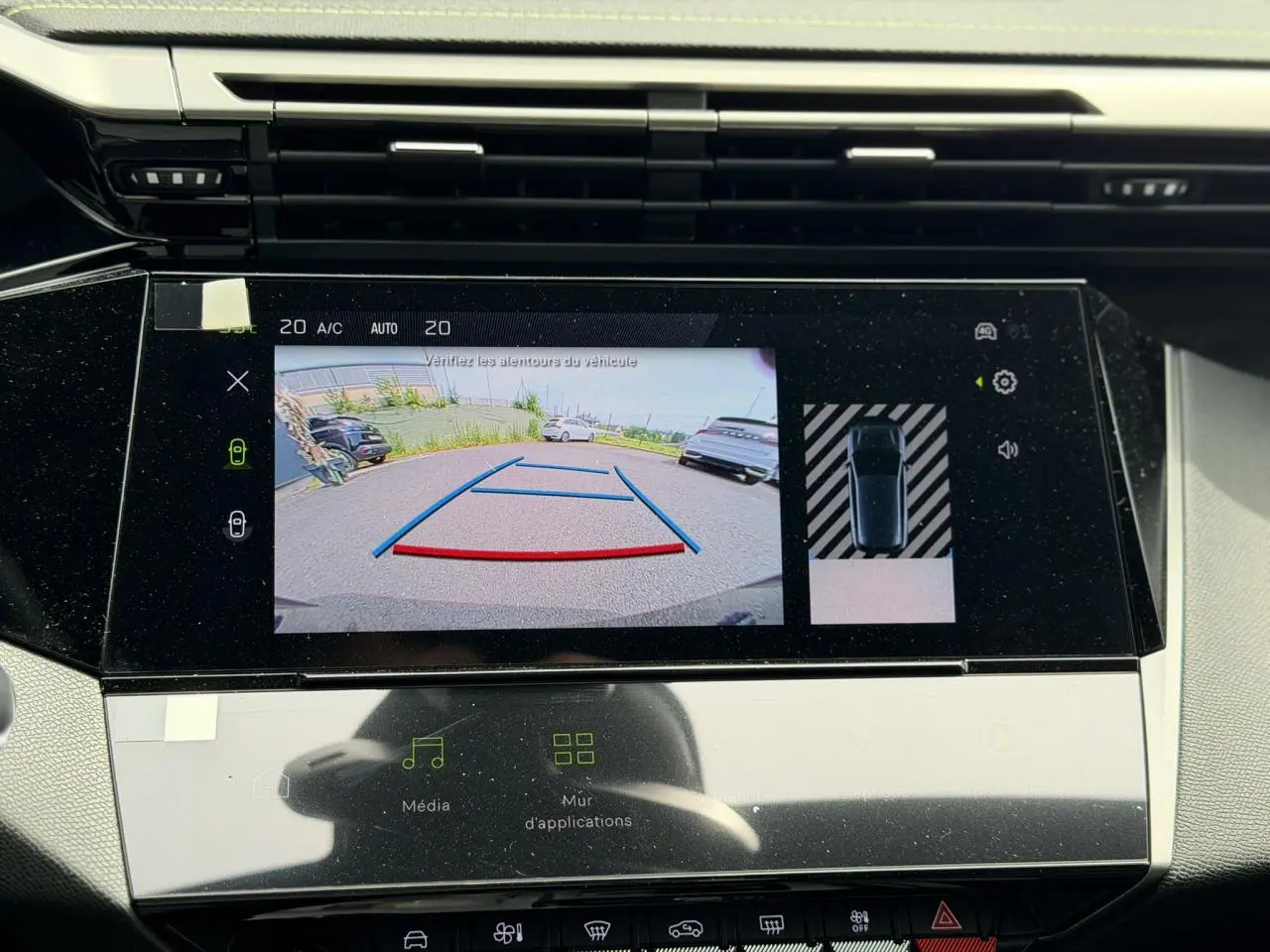 Vue rapprochée de l'écran tactile intérieur affichant la caméra de recul et l'aide au stationnement du Peugeot 308 gris Artense.