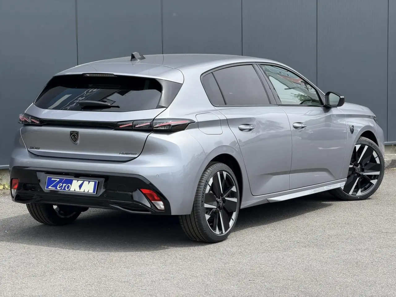 Peugeot 308 NV Hybrid gris Artense vue 3/4 arrière droit, jantes bi-ton et feux arrière LED 3 griffes.
