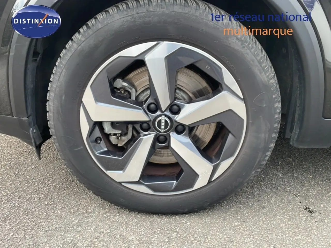 Gros plan sur la roue avant gauche du Nissan Qashqai noir métal 2023 avec jante alliage bicolore distinctive.