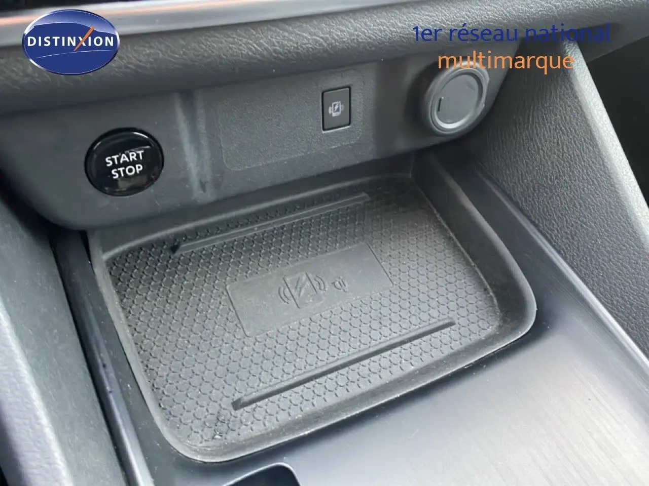 Gros plan sur la console centrale du Nissan Qashqai noir, montrant le bouton Start/Stop et un espace de recharge sans fil.