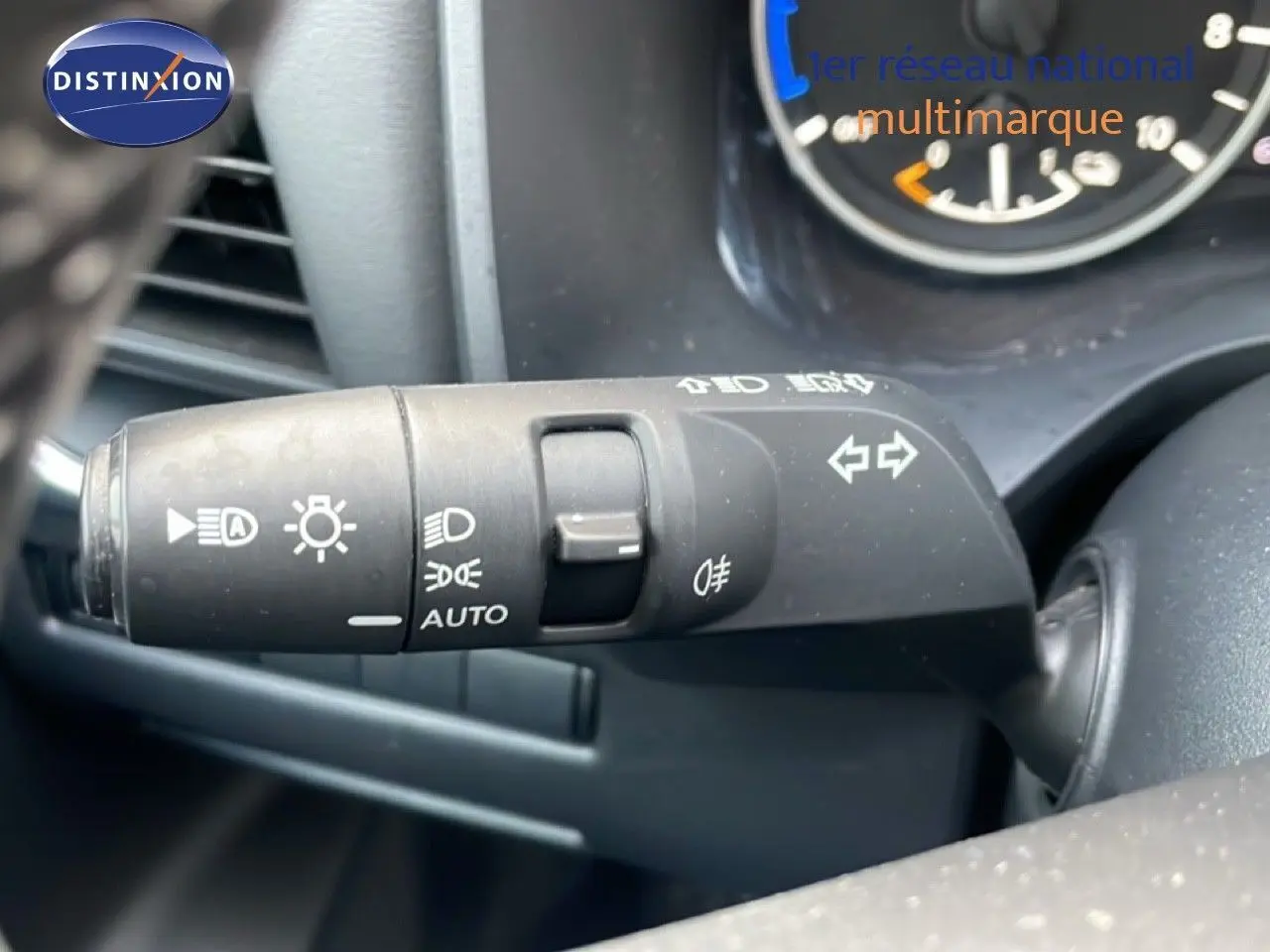 Gros plan sur la commande des feux et clignotants du Nissan Qashqai noir métal, tableau de bord partiellement visible.