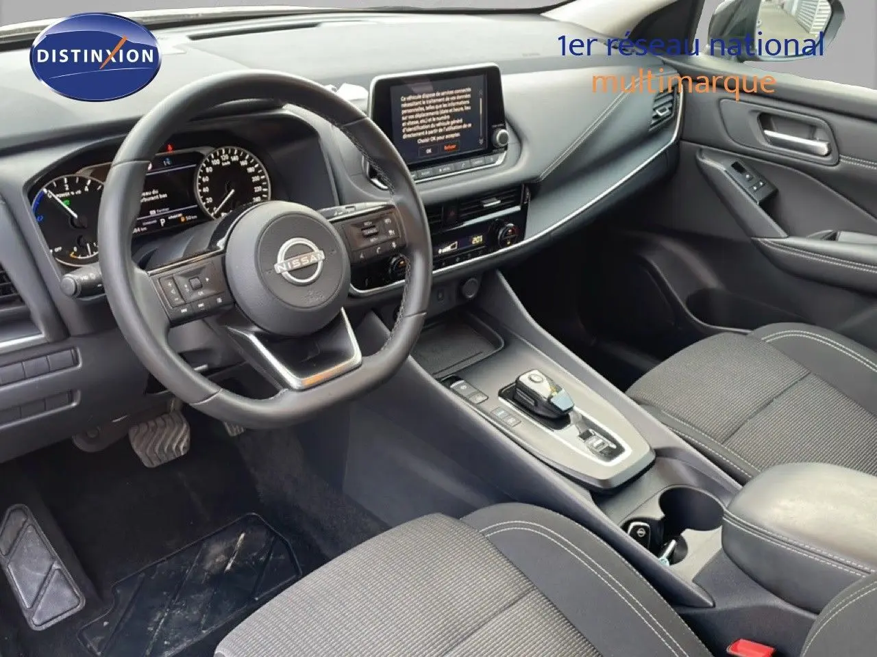 Vue intérieure côté conducteur du Nissan Qashqai 1.5 E-POWER 2023, avec volant cuir noir et console centrale moderne.