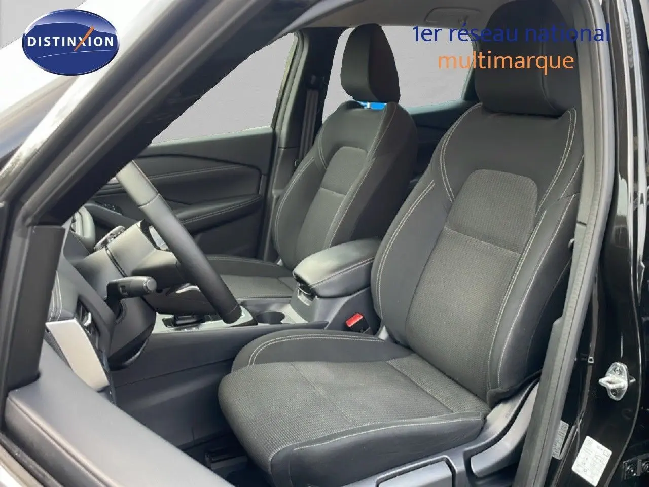 Vue intérieure côté conducteur du Nissan Qashqai 2023 noir métal, mettant en valeur les sièges tissu avec surpiqûres contrastées.