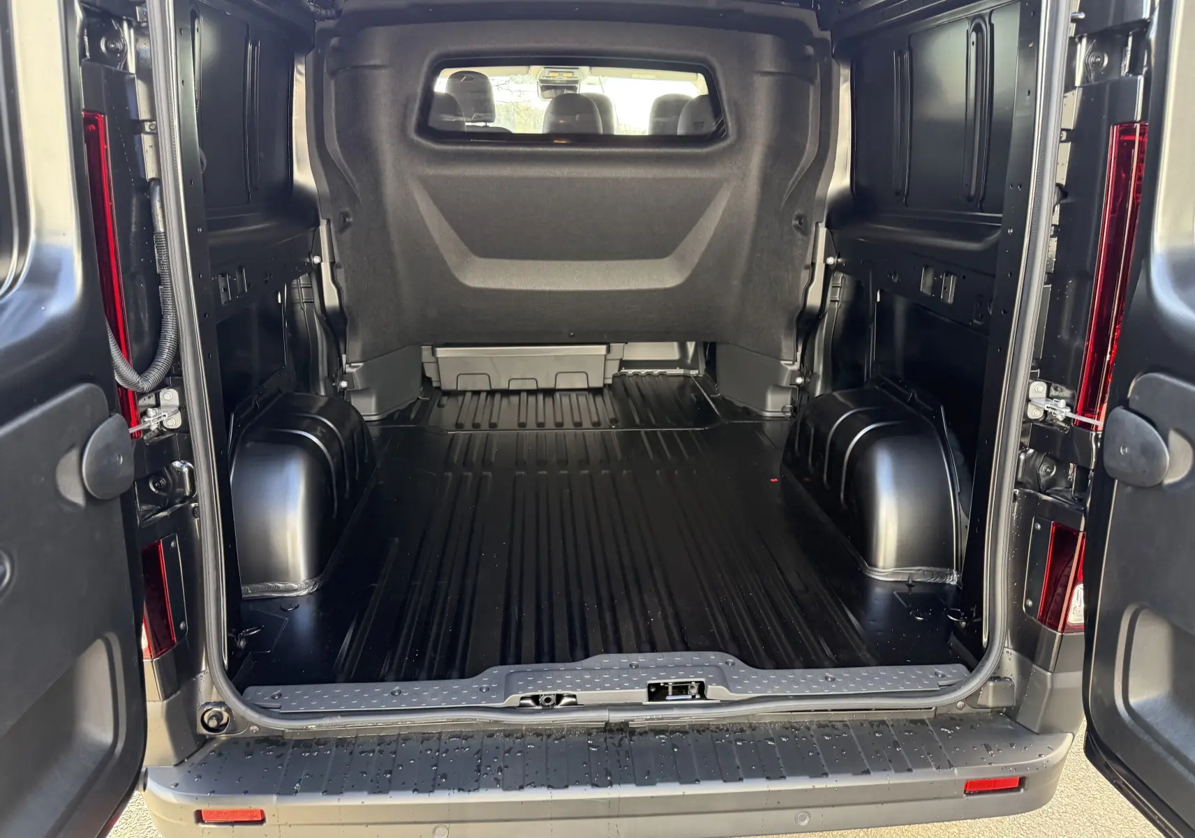 Vue arrière ouverte du Renault Trafic cabine approfondie noir, montrant l'espace de chargement vide et les portes battantes ouvertes.