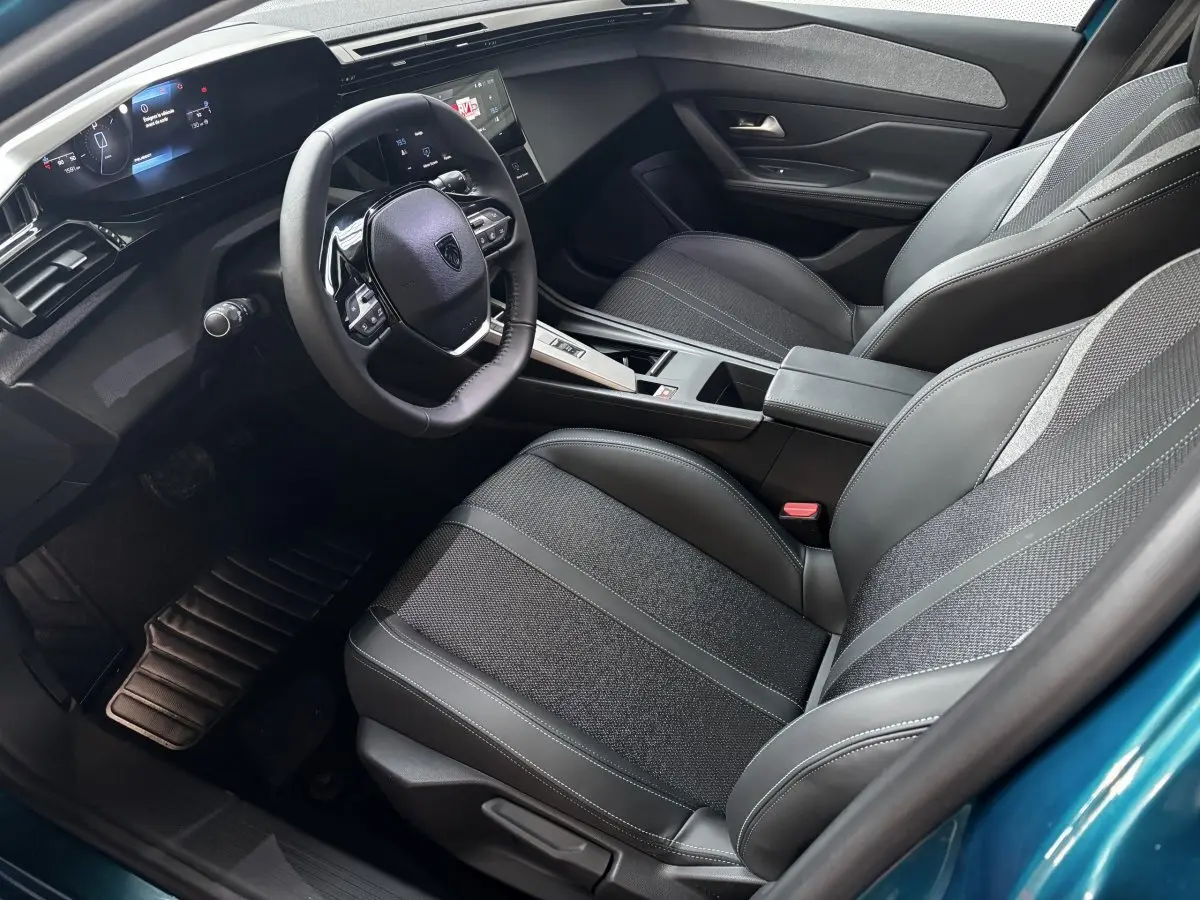 Vue intérieure côté conducteur de la Peugeot 308 Hybrid bleu, volant cuir multifonctions et écran numérique 10 pouces.