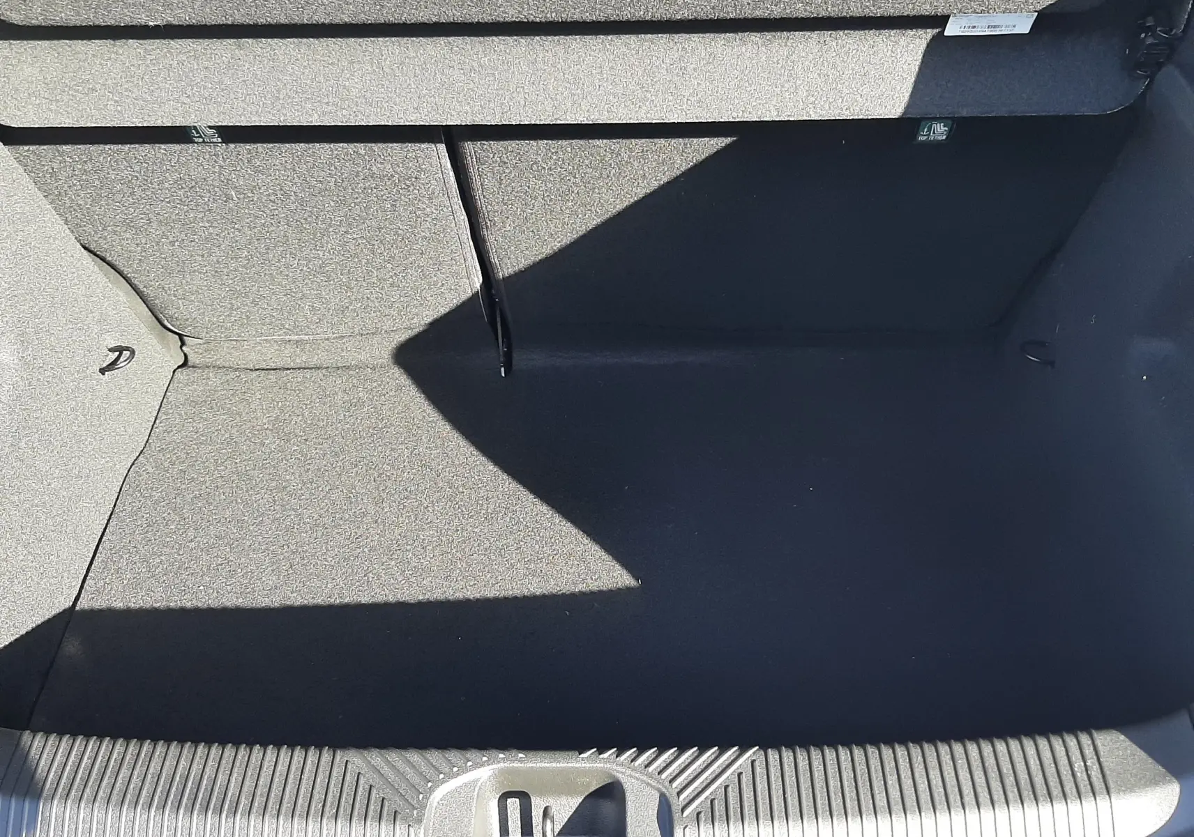 Coffre ouvert vu de dessus d’une Renault Clio VI TCE 115CH TECHNO gris Rafale, intérieur noir et tapis de sol.