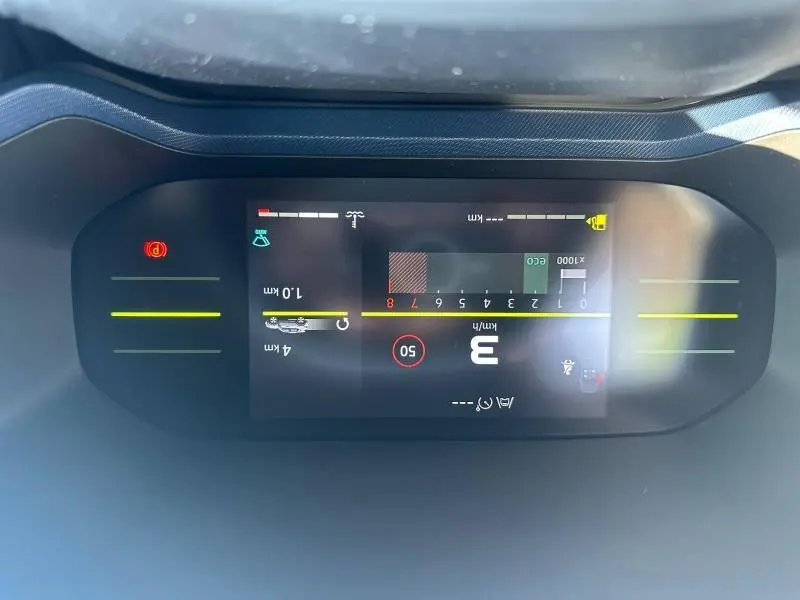 Vue rapprochée de l'écran numérique du tableau de bord du Dacia Duster blanc, affichant la vitesse et les alertes.