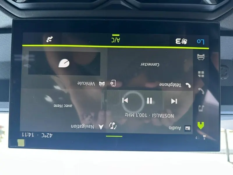 Écran tactile central du tableau de bord du Dacia Duster blanc 2025 affichant les commandes audio et de navigation.