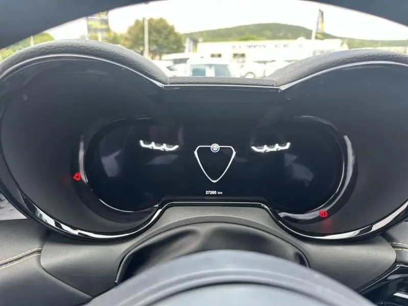 Vue rapprochée du tableau de bord numérique de l'Alfa Romeo Tonale gris foncé, affichant le logo central et 27 285 km au compteur.