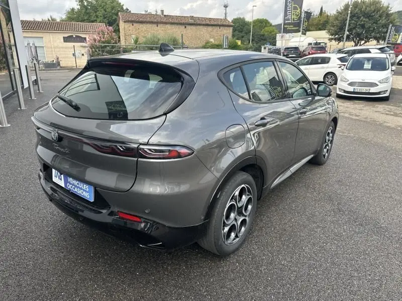 Vue 3/4 arrière droite d'une Alfa Romeo Tonale gris foncé métal 2024 avec jantes distinctives et feux arrière effilés.