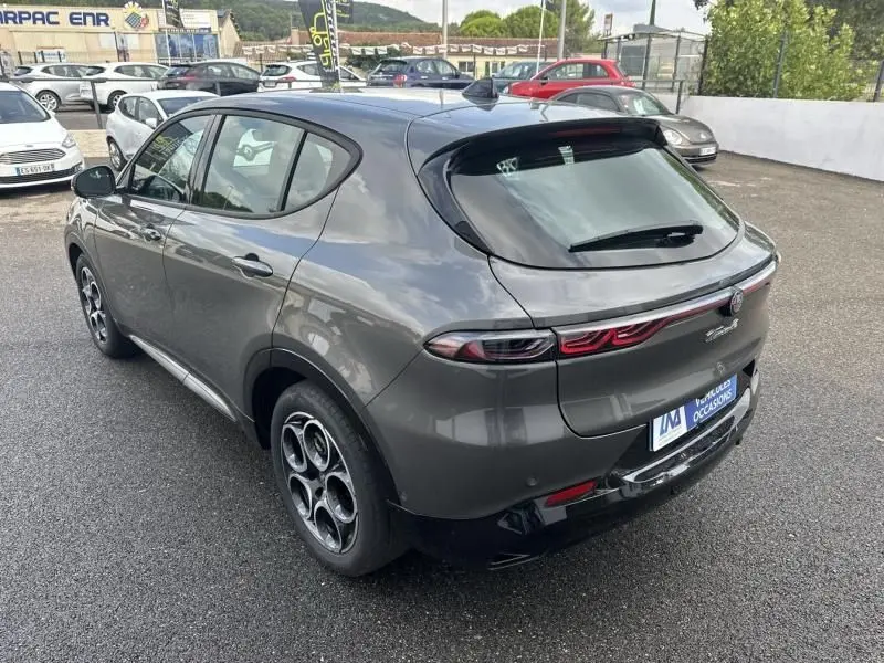 Vue 3/4 arrière droite de l'Alfa Romeo Tonale 1.5 Hybrid gris foncé métallisé avec feux arrière reliés par un bandeau lumineux.