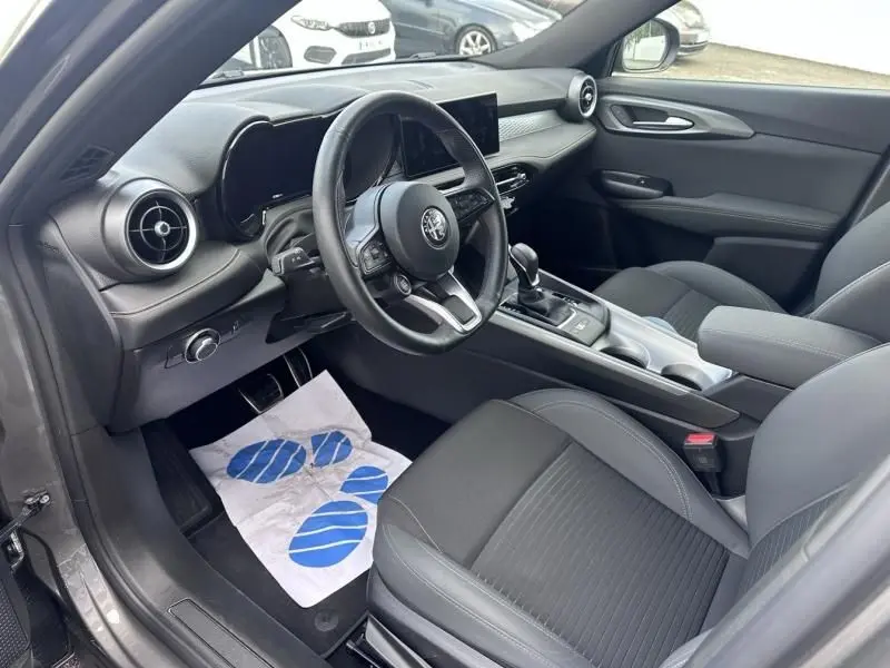 Intérieur de l'Alfa Romeo Tonale 1.5 Hybrid gris foncé, vue côté conducteur sur le tableau de bord et les sièges noirs.
