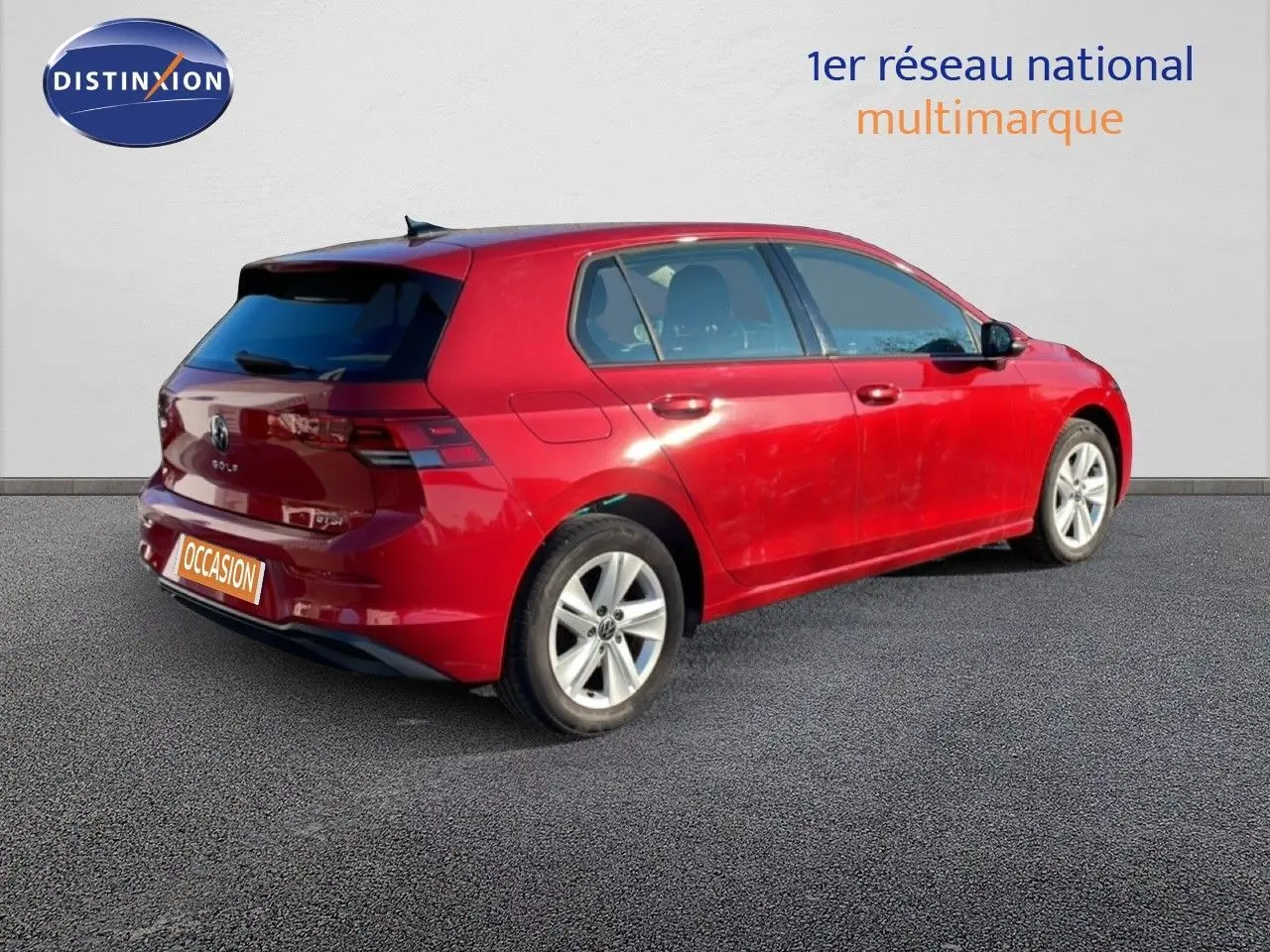 Vue 3/4 arrière droite d'une Volkswagen Golf VIII rouge Roi Metal avec jantes alliage et vitres teintées.