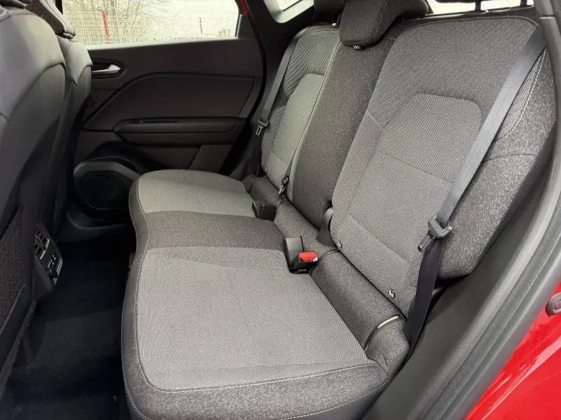 Vue intérieure côté droit des sièges arrière gris du Renault Captur 2025 Rouge Flamme avec ceinture de sécurité visible.