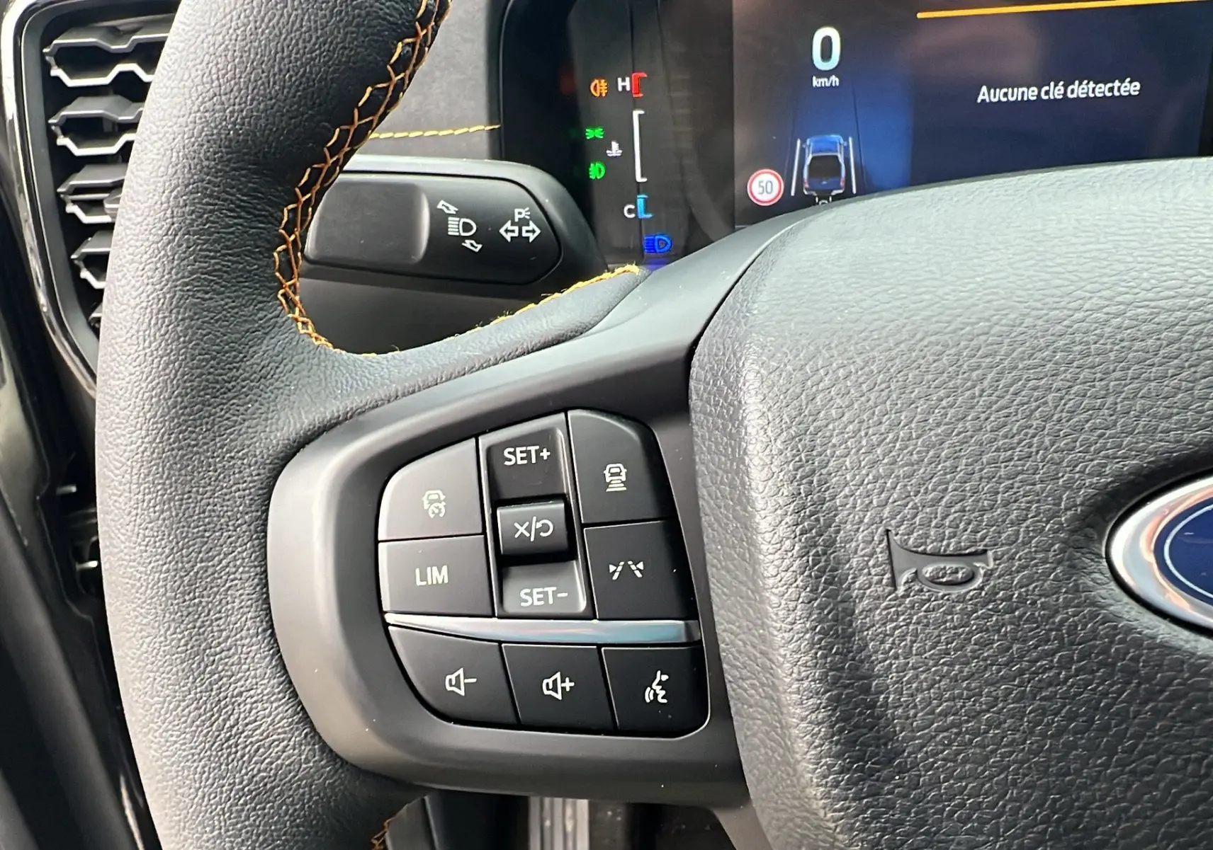 Gros plan sur le volant cuir noir avec commandes multifonctions du Ford Ranger Wildtrak X 2026, affichage digital en arrière-plan.