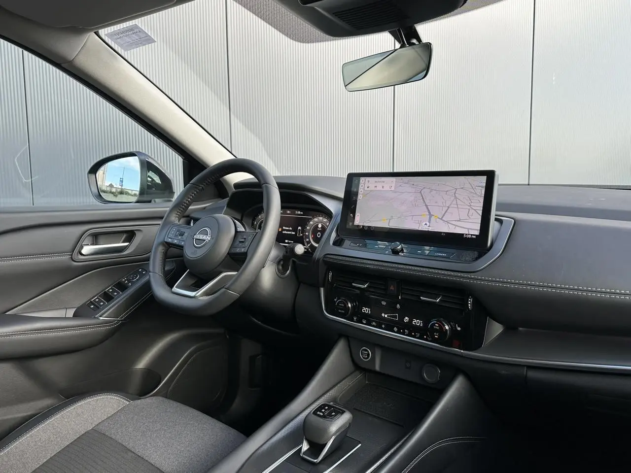 Vue intérieure côté conducteur du Nissan Qashqai 2025 noir nacré, avec tableau de bord numérique et écran tactile central affichant la navigation.