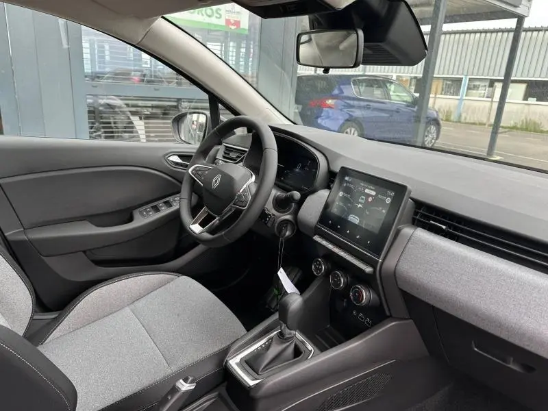 Vue intérieure côté conducteur de la Renault Clio 2025 gris Rafale, volant multifonction et écran tactile central visible.