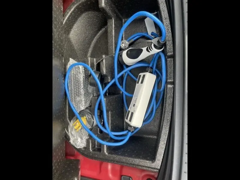 Gros plan sur le câble de recharge bleu dans le coffre d’un Hyundai Kona électrique rouge métal 2021.