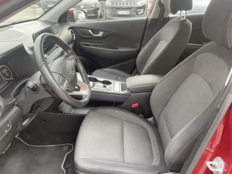 Intérieur du Hyundai Kona électrique 2021 vu côté conducteur, sièges gris et tableau de bord moderne.