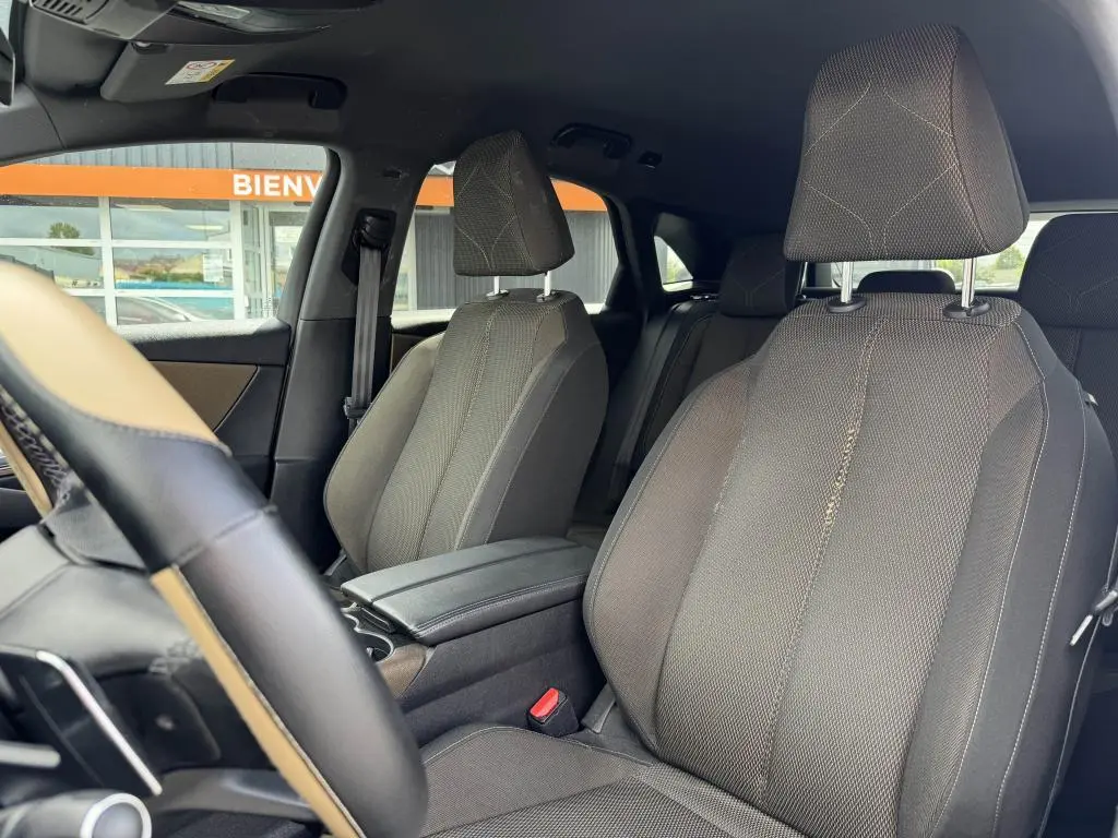 Vue intérieure sur les sièges avant en tissu bronze du DS7 Crossback gris, avec accoudoir central et volant partiel visible.