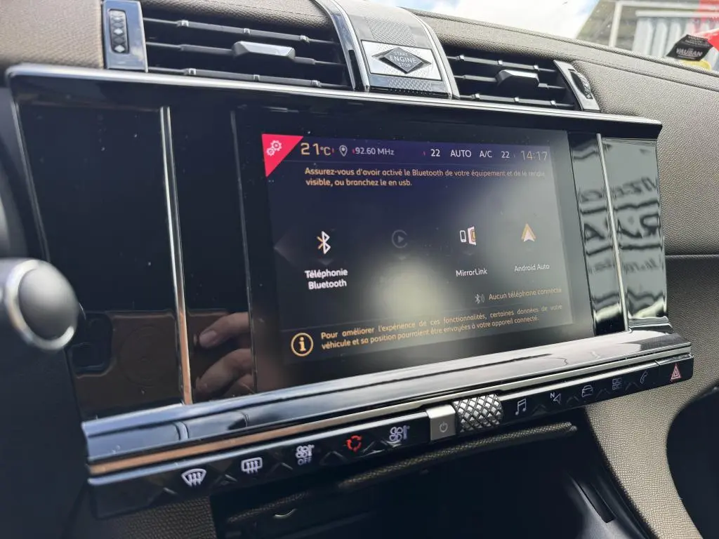 Vue rapprochée de l'écran tactile central noir brillant du tableau de bord du DS7 Crossback 2022 avec commandes climatisation.