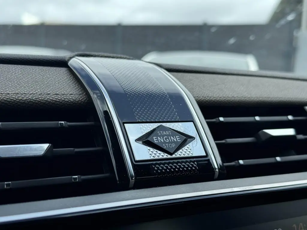 Gros plan sur le bouton Start Engine Stop entouré de décor noir et chrome dans le tableau de bord du DS7 Crossback gris.