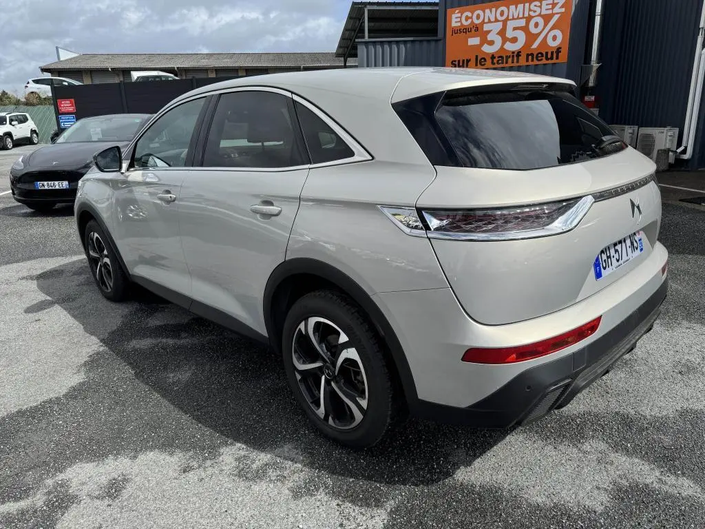 DS7 Crossback gris métallisé vu en 3/4 arrière côté gauche, avec feux arrière 3D et vitres teintées.