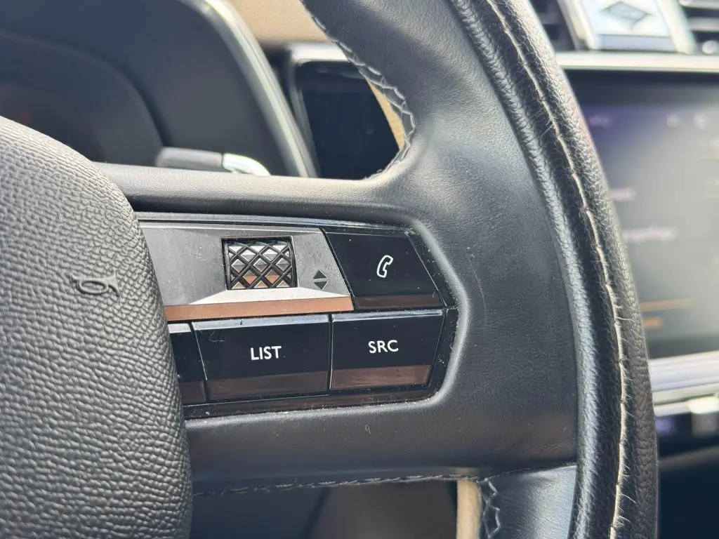 Gros plan sur les commandes gauche du volant cuir noir du DS7 Crossback 2022 avec touches LIST et SRC.