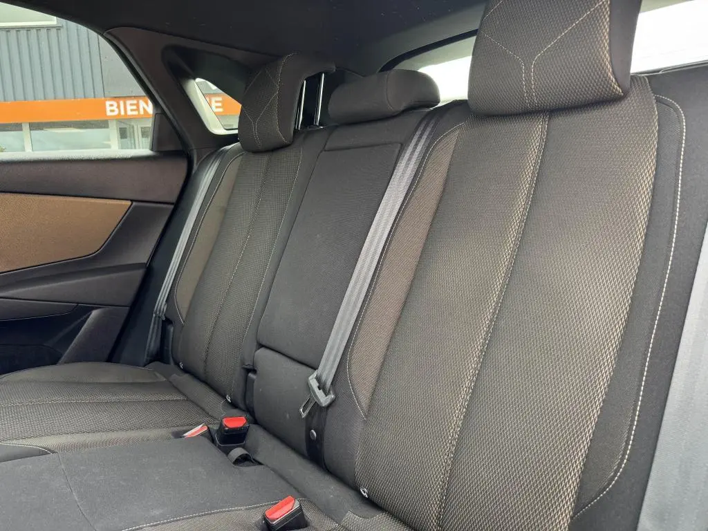 Vue latérale droite de la banquette arrière en tissu bronze du DS7 Crossback gris, avec appuie-têtes et ceintures visibles.