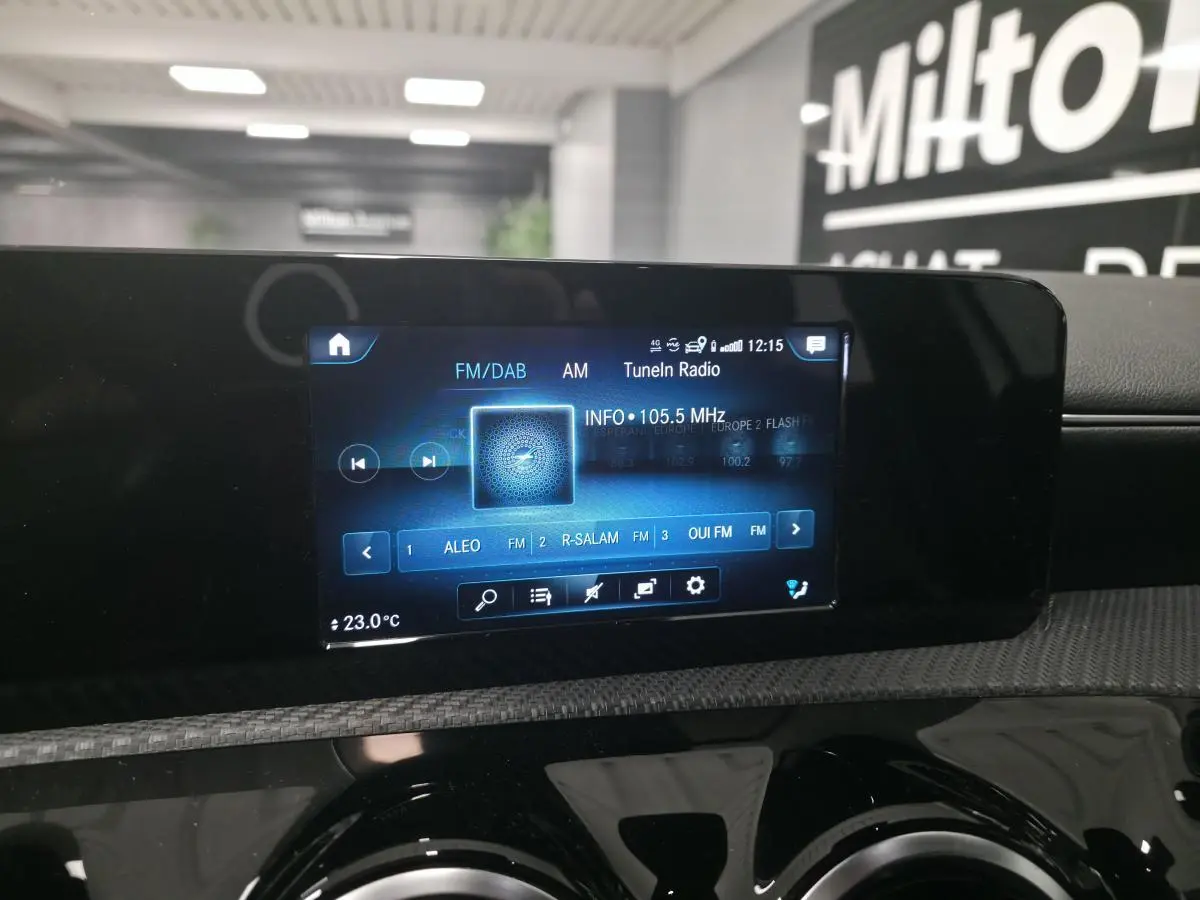 Écran tactile multimédia MBUX affichant la radio FM/DAB dans l'habitacle d'une Mercedes Classe A blanche.