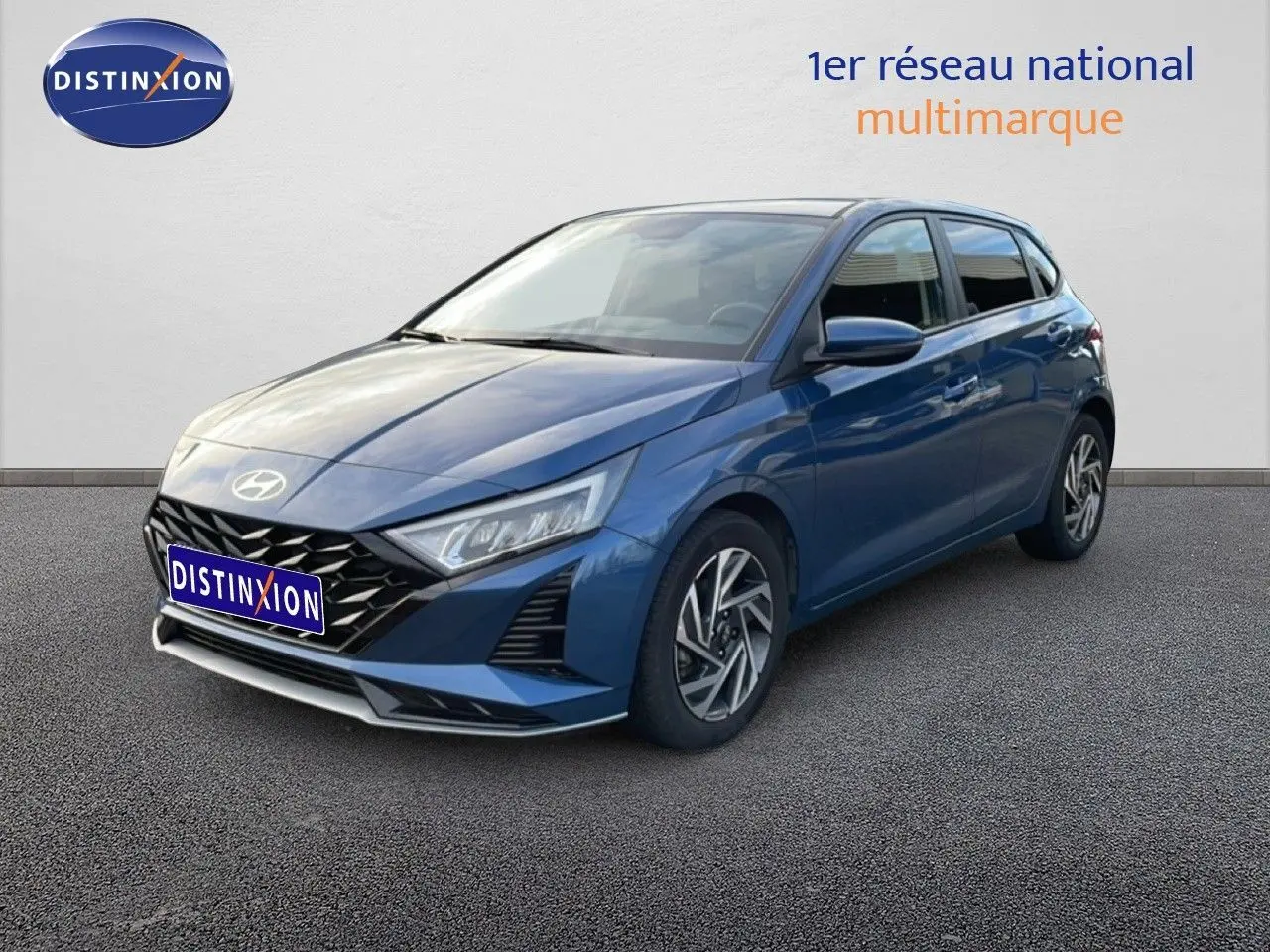 Vue 3/4 avant droit d'une Hyundai i20 2025 bleu vibrant metal avec calandre noire et phares LED anguleux.