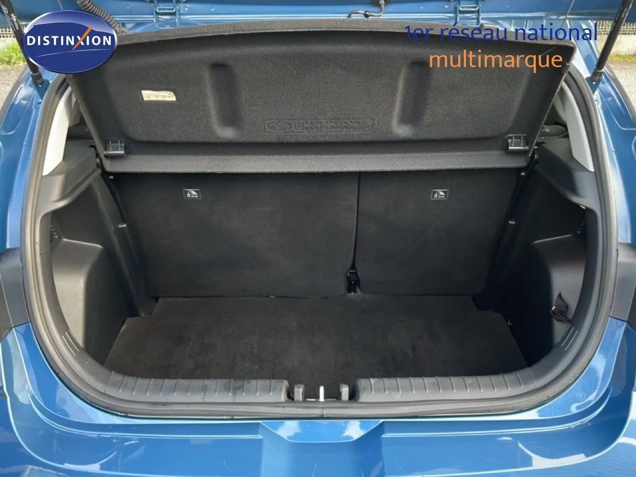 Coffre ouvert vu de l'arrière d'une Hyundai i20 1.0 TGDI 100CH KLASS bleu vibrant metal, intérieur noir et tapis de sol.