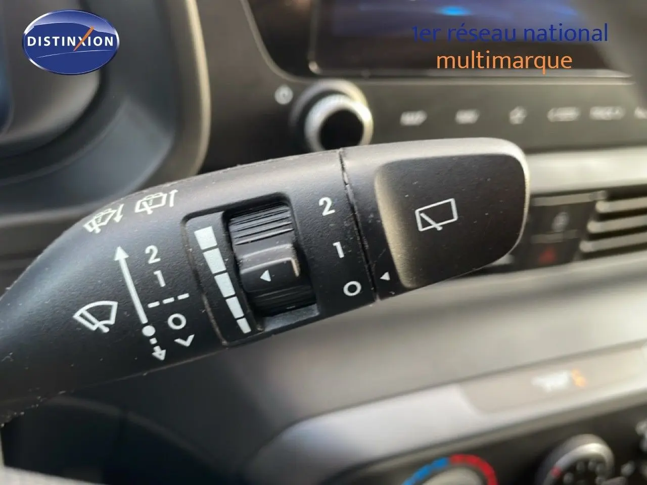 Gros plan sur la commande des essuie-glaces du Hyundai i20 2025 en Bleu Vibrant Metal, intérieur tableau de bord flou.