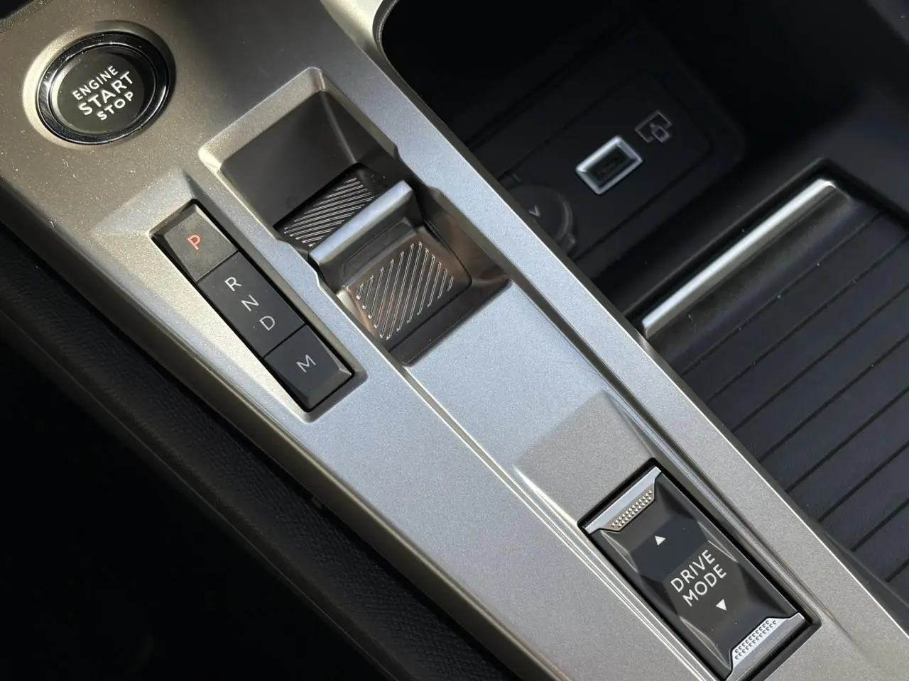 Vue rapprochée de la console centrale argentée de la Peugeot 308 Hybrid avec sélecteur de boîte auto et bouton Drive Mode.