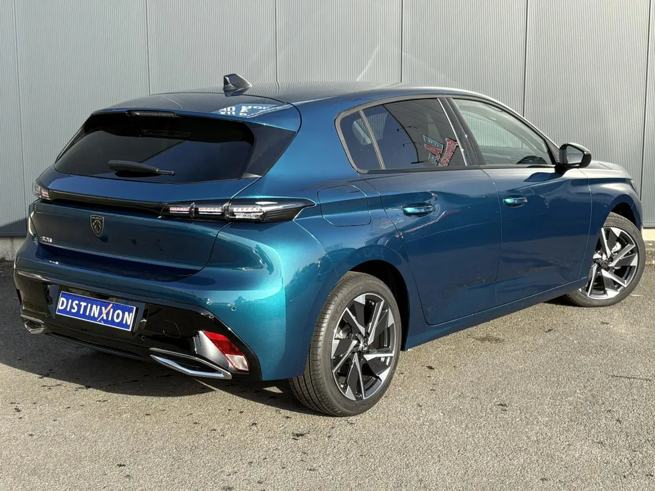Vue 3/4 arrière droite d'une Peugeot 308 Hybrid 2025 en Bleu Obsession avec jantes alliage et vitres surteintées.
