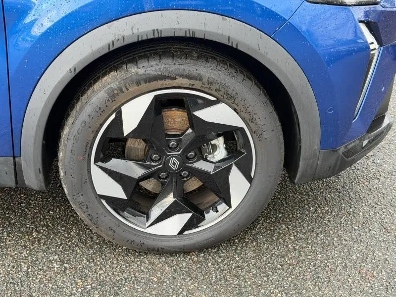 Gros plan sur la roue avant droite du Renault Captur 2025 bleu Iron avec jante noire et blanche au design géométrique.