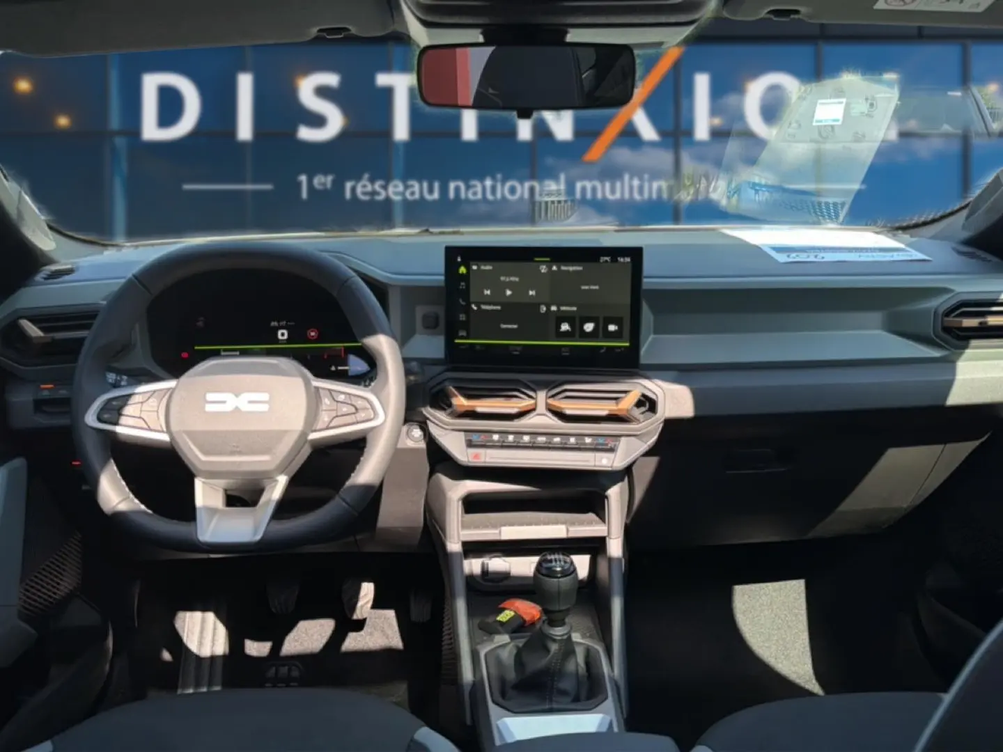 Intérieur avant du Dacia Bigster blanc 2026, vue du poste de conduite avec volant multifonction et écran tactile central.