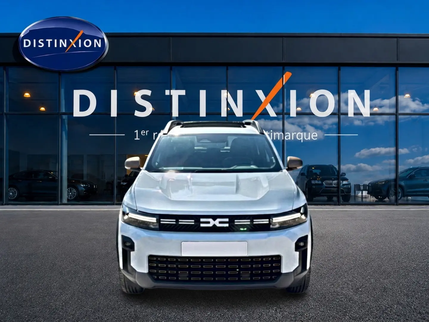 Vue frontale du Dacia Bigster blanc 2026 avec calandre noire distinctive et barres de toit visibles.