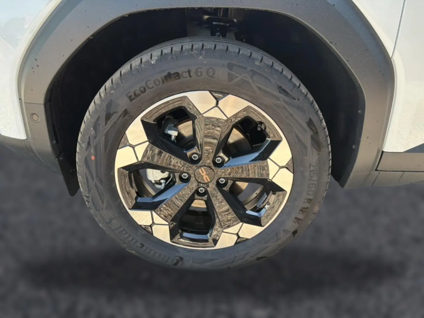 Gros plan sur la roue avant droite blanche du Dacia Bigster avec jante alu bicolore noire et argentée.