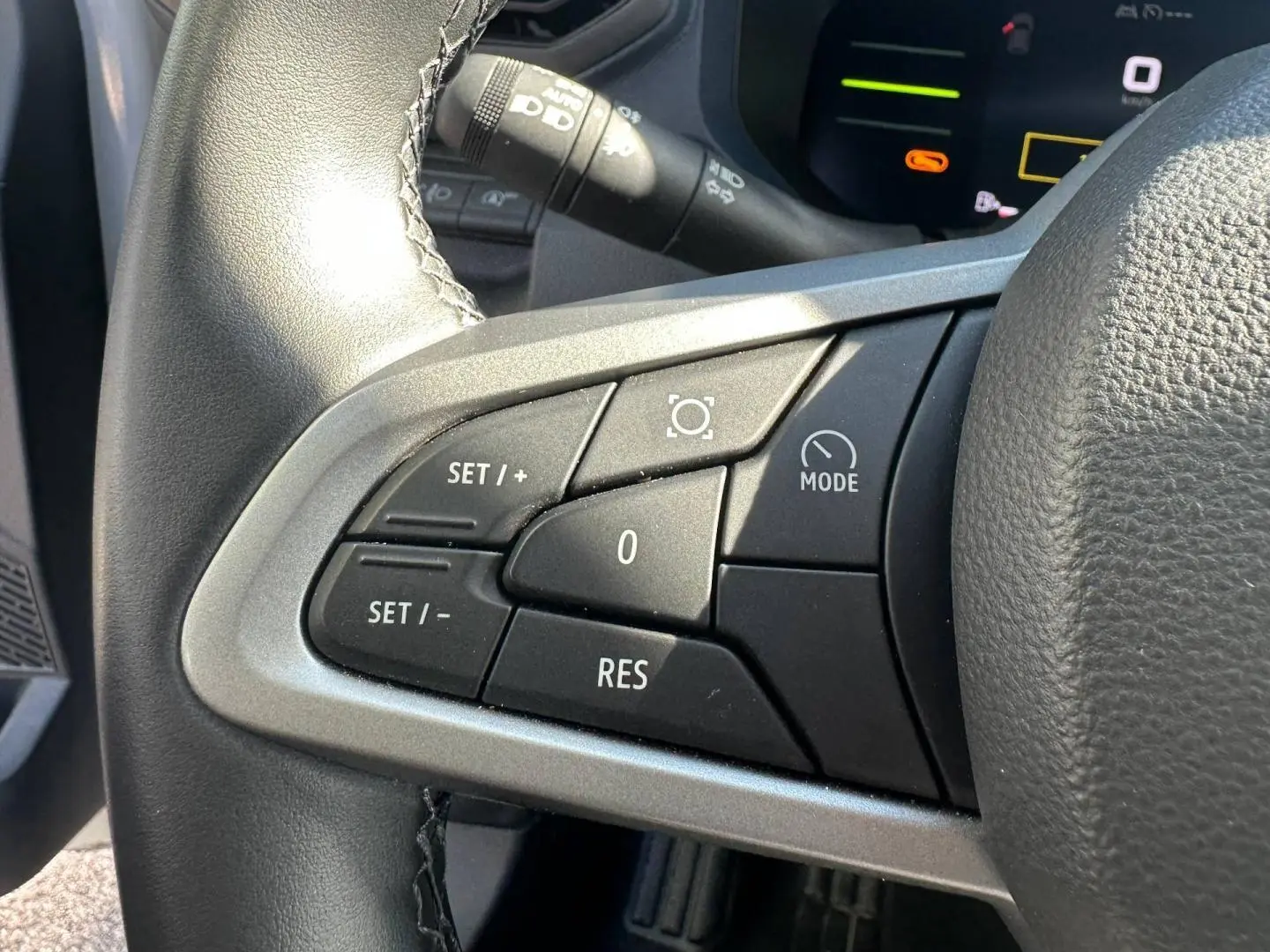 Gros plan sur les commandes noires du volant multifonction côté gauche du Dacia Duster 2025 couleur Sandstone.