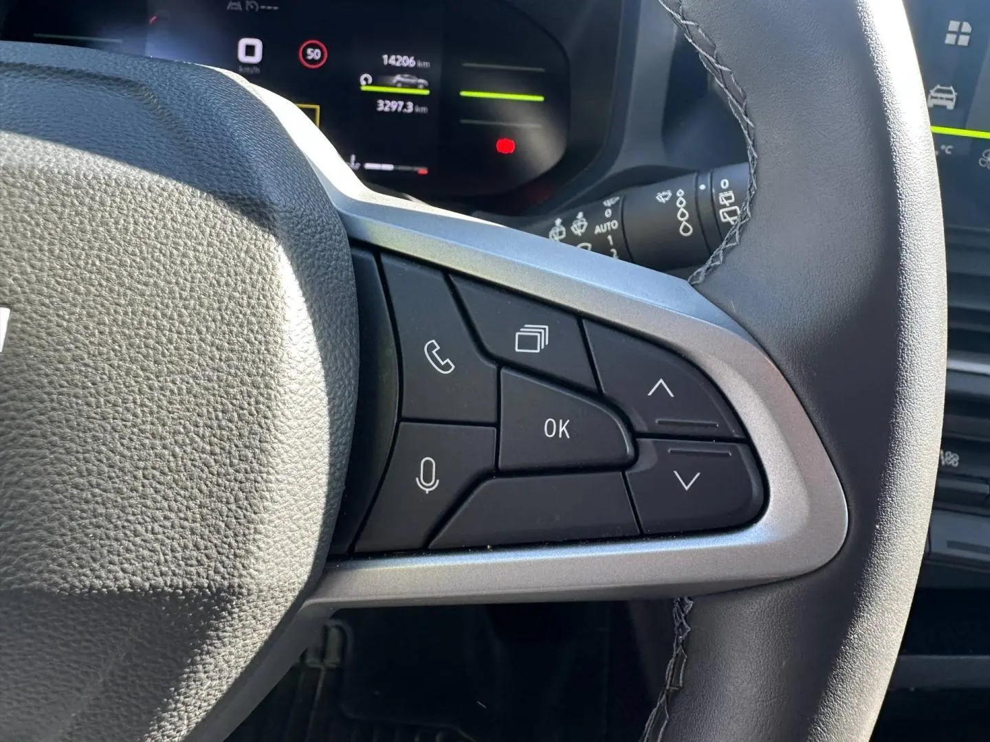 Gros plan sur les commandes multifonctions à droite du volant du Dacia Duster 2025, intérieur noir et gris.