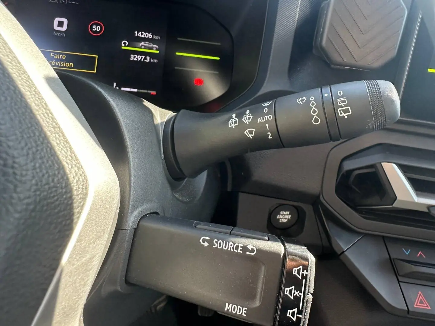 Gros plan sur la commande multifonction et le tableau de bord numérique du Dacia Duster 2025, intérieur noir.
