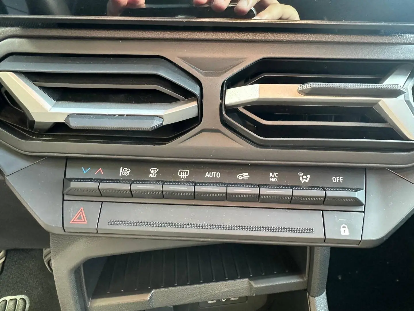 Vue rapprochée de la console centrale du Dacia Duster 2025, boutons de climatisation et sorties d’air noires.