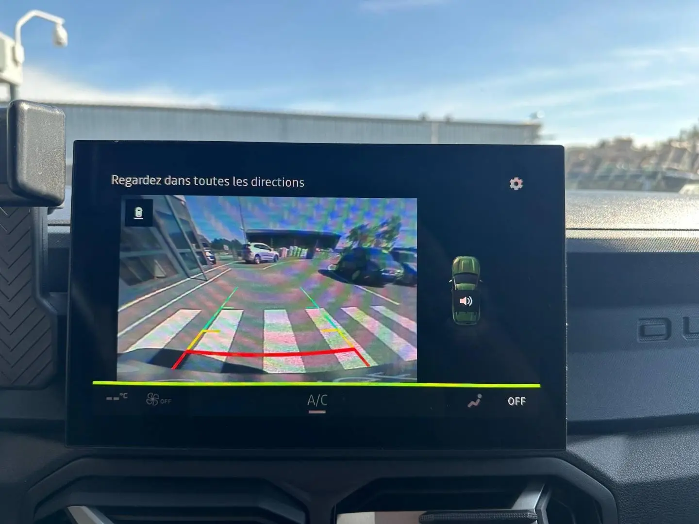 Écran tactile intérieur du Dacia Duster 2025 affichant la caméra de recul avec vue arrière en extérieur.