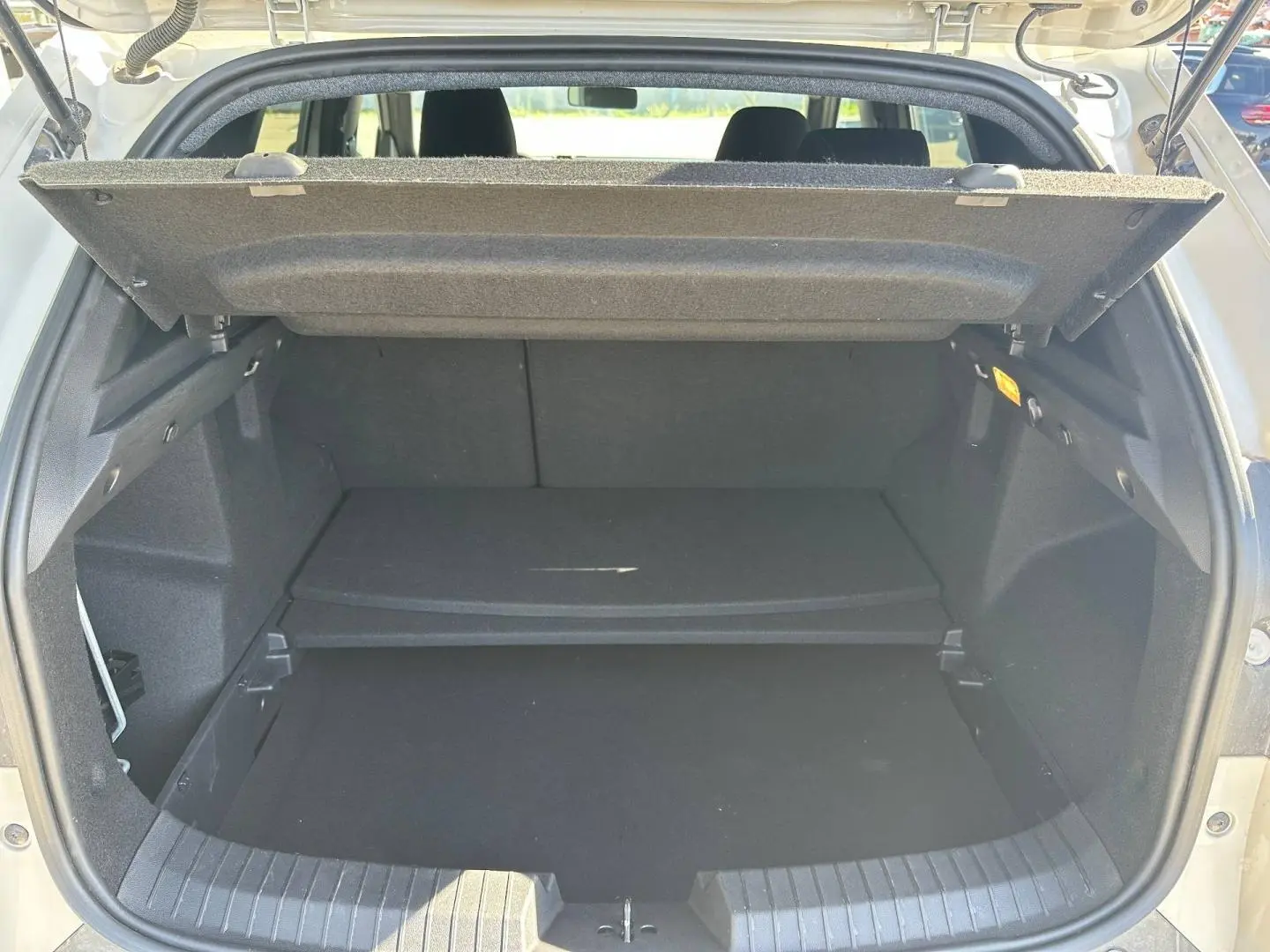Coffre ouvert du Dacia Duster 2025 couleur Sandstone, montrant la tablette cache-bagages et l’espace de rangement.