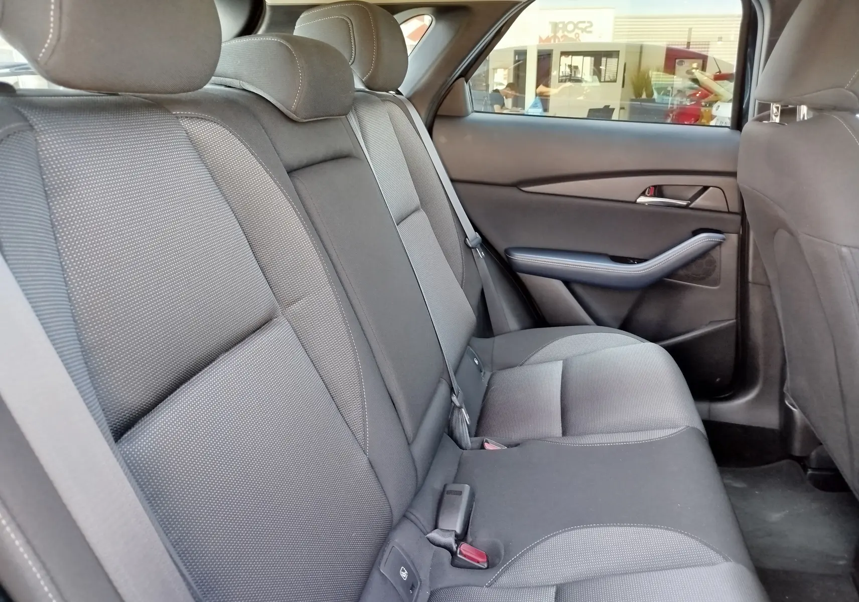 Vue intérieure des sièges arrière en tissu noir du Mazda CX-30 2020, côté droit avec ceinture de sécurité visible.